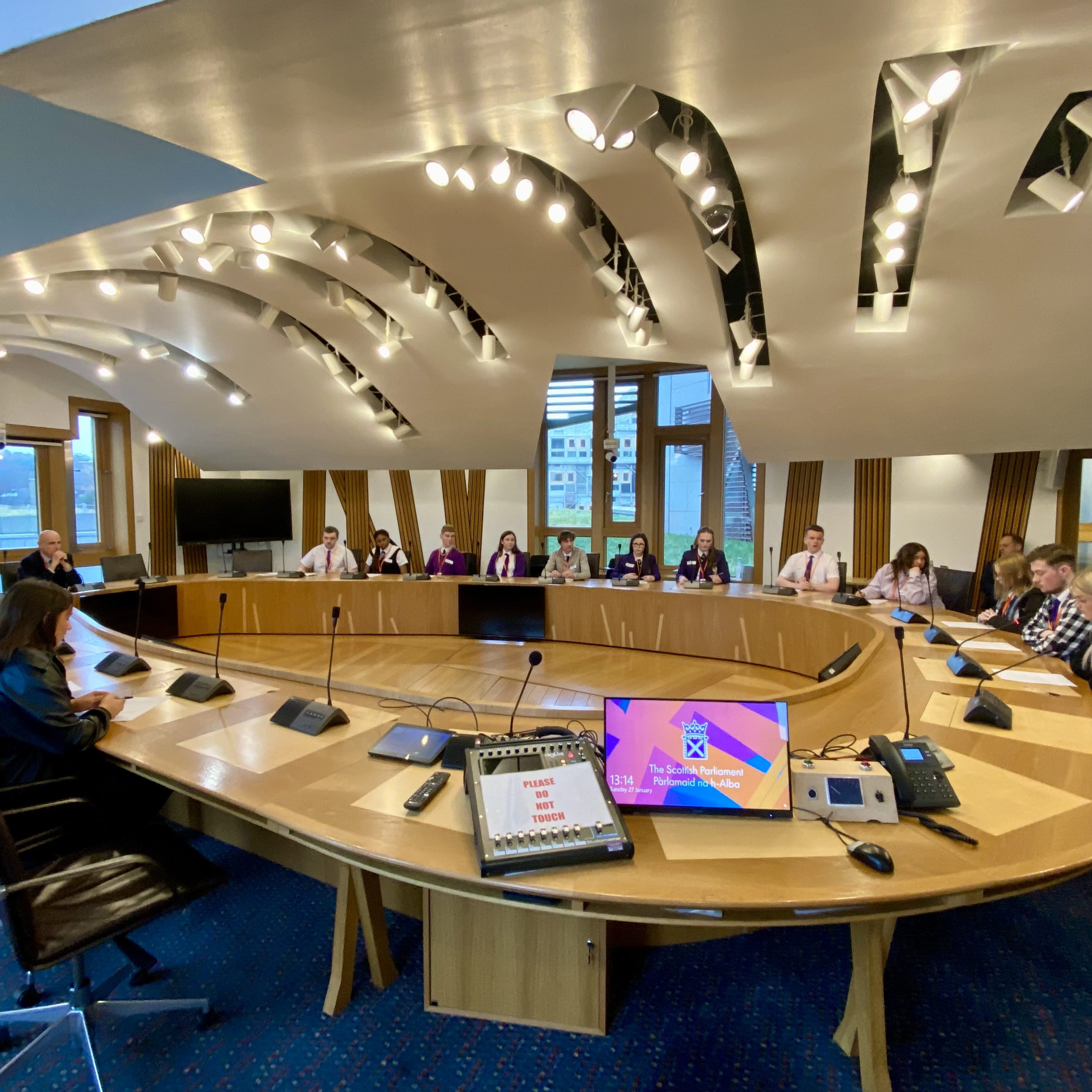 Pupils sat around a table in a Scottish Parliament Committee Room.